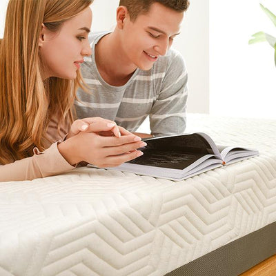 woman and man couple reading a book together on top of their mattress