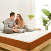 man and woamn couple talks and sits on top of their latex mattress